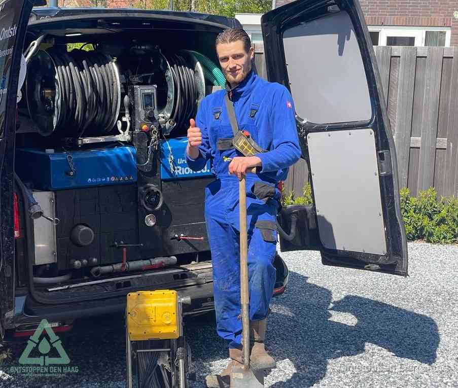 Een tevreden monteur met opgestoken duim naast de bestelbus, slim ingrijpen bespaart kosten bij een verstopte afvoer in Den Haag