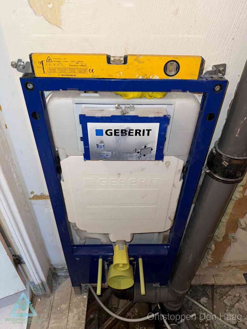 Een Geberit inbouwreservoir met frame voor een hangtoilet tegen de wand, met de afvoerbocht naar de vloer, kenmerkend voor een verstopt hangtoilet in Den Haag