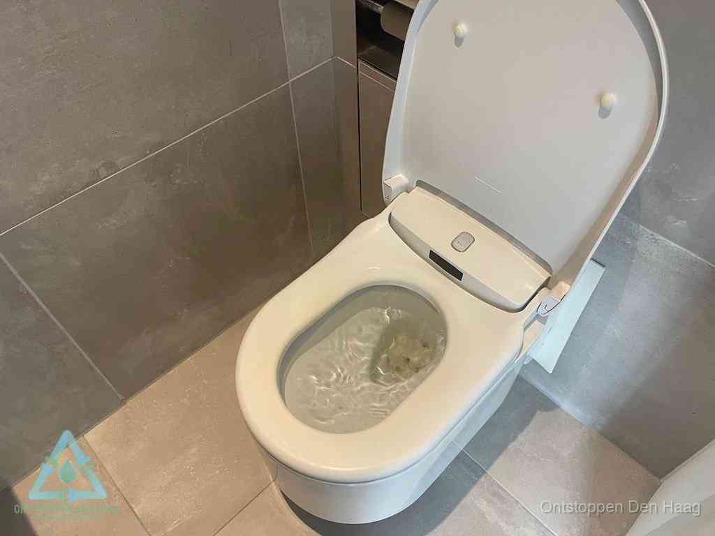 Een toiletpot vol troebel water met drijvend papier en restanten, de meest voorkomende oorzaak van een verstopte wc in Den Haag