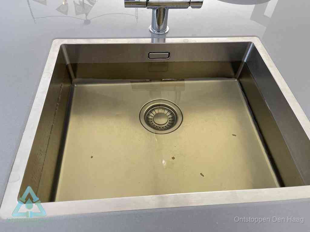 Stilstaand water in een rvs spoelbak dat niet wegloopt, een duidelijk signaal van een gootsteenverstopping in Den Haag