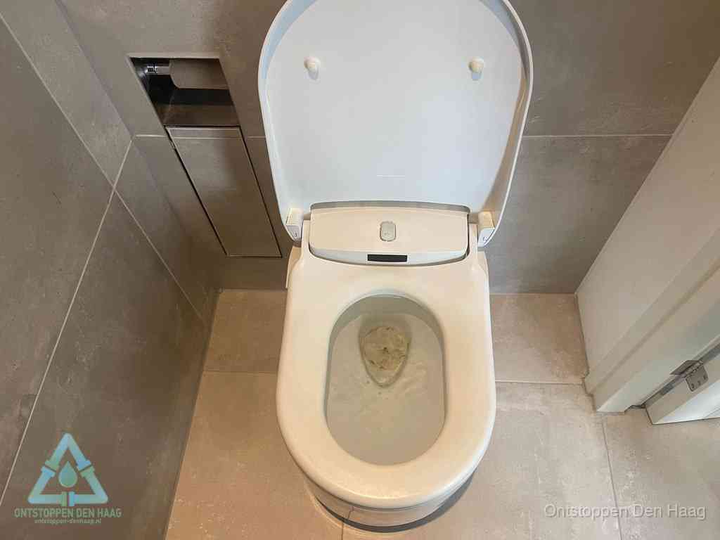 Een wit hangtoilet waarin een prop wc-papier op het water blijft drijven, een duidelijk signaal van een verstopte wc in Den Haag