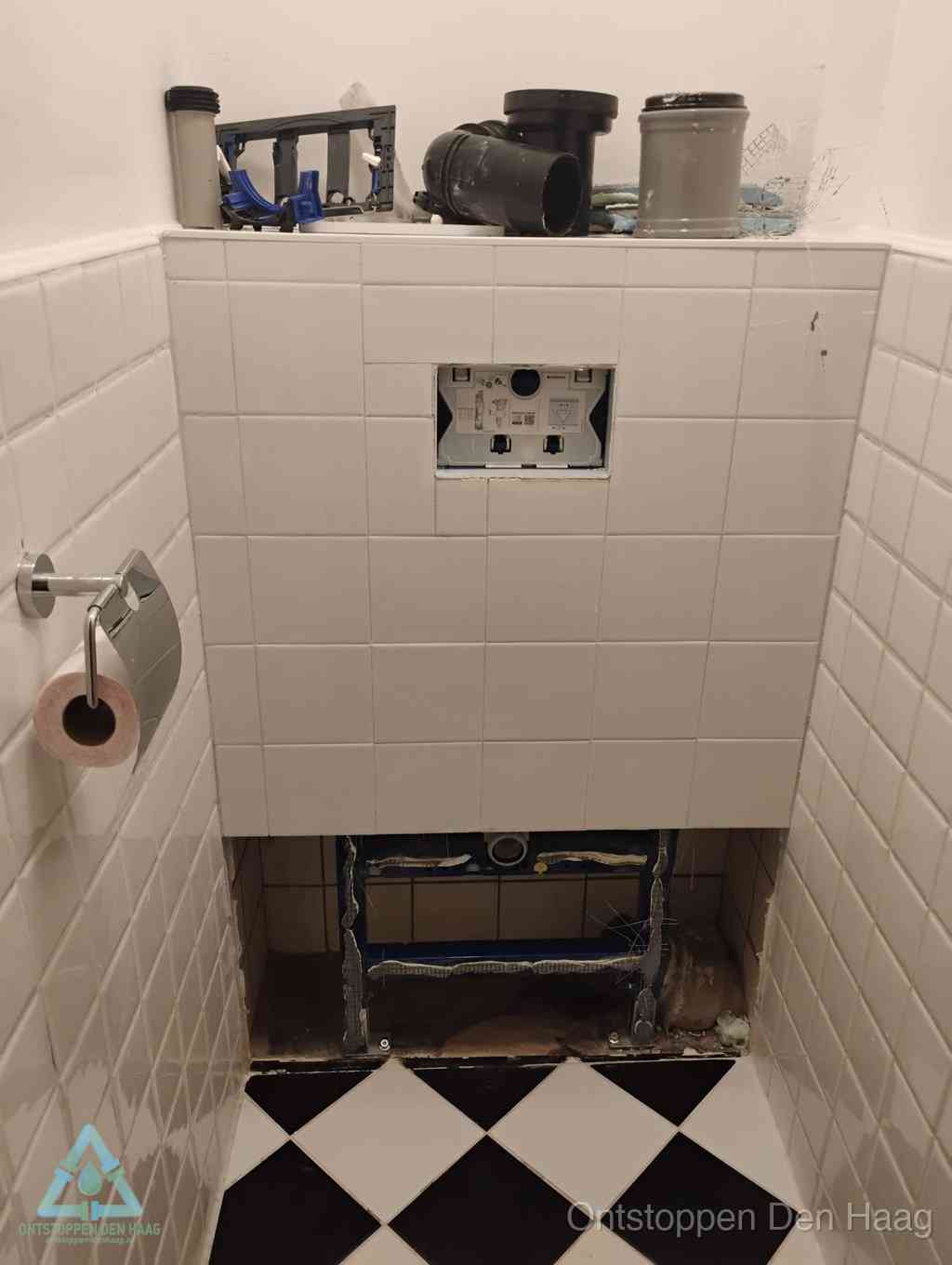 Een toiletruimte waar het hangtoilet en de inbouwreservoir-onderdelen zijn vrijgelegd voor onderhoud, periodiek nazicht voorkomt een wc-verstopping in Den Haag